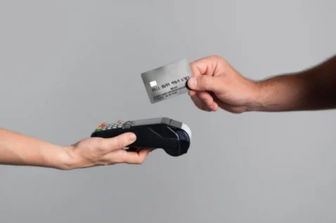 Mão aproximando cartão de crédito de maquininha de pagamento, ilustrando o parcelamento sem juros no Mercado Livre como estratégia para vender mais
