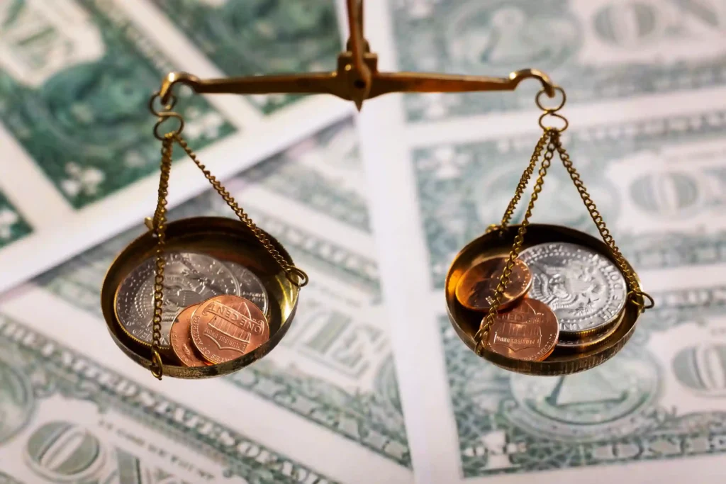Balança de precisão dourada com moedas americanas nos dois pratos sobre notas de dólar