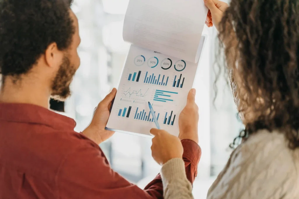 Duas pessoas analisando relatório com gráficos e percentuais, ilustrando como monitorar concorrentes Mercado Livre
