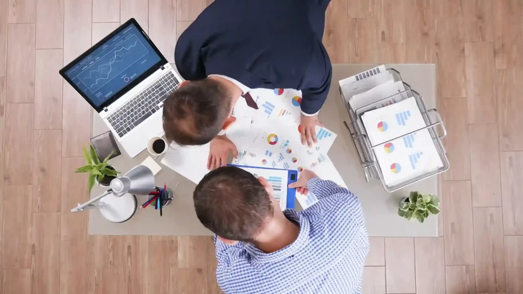 Equipe reunida analisando gráficos e relatórios de vendas em uma mesa de trabalho
