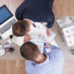 Equipe reunida analisando gráficos e relatórios de vendas em uma mesa de trabalho