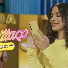 Frame de campanha publicitária Anittaço do Mercado Livre com celebridade de roupa amarela usando smartphone, letreiro "Moda" ao fundo
