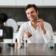Homem sorridente gravando vídeo com produtos de beleza masculina Mercado Livre sobre a bancada