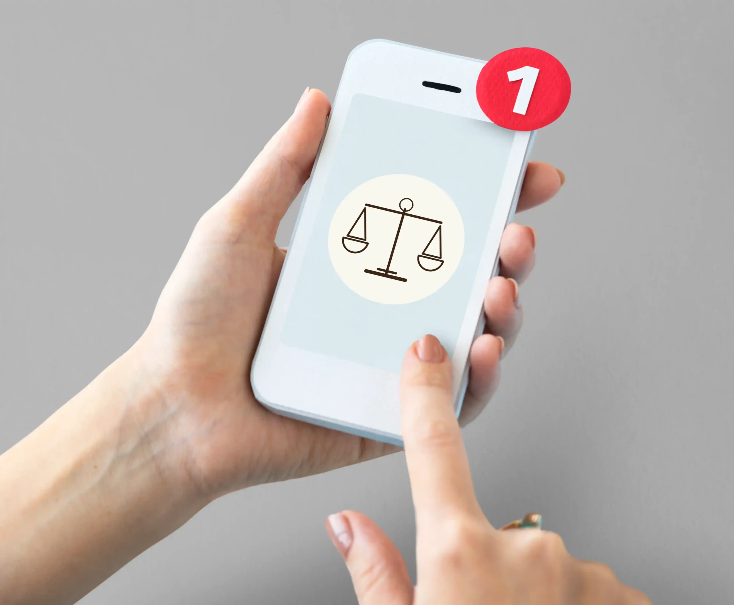Mãos segurando smartphone com ícone de balança da justiça na tela e notificação com número um, fundo cinza