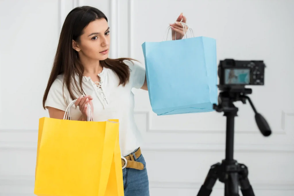 Mulher gravando vídeo mostrando sacolas coloridas de compra, ilustrando como criar anúncio Mercado Livre com boas fotos do produto