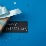 Presente embrulhado em papel kraft com laço azul claro e cartão escrito "Happy Father's Day" sobre fundo azul com estrelinhas decorativas