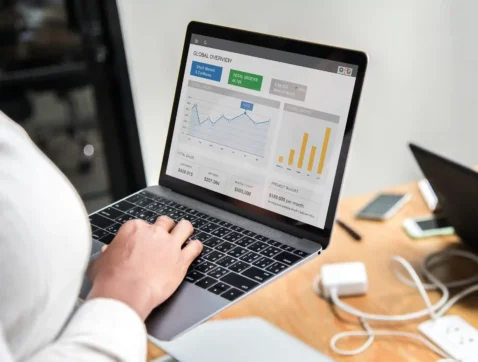 Pessoa analisando dashboard de performance no marketplace em um notebook com gráficos e indicadores de vendas.