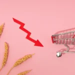 Seta vermelha em queda ao lado de carrinho de compras vazio e espigas de trigo, ilustrando o varejo em queda 2026
