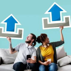 Homem e mulher sentados em um sofá seguram celulares e grandes setas azuis apontadas para cima