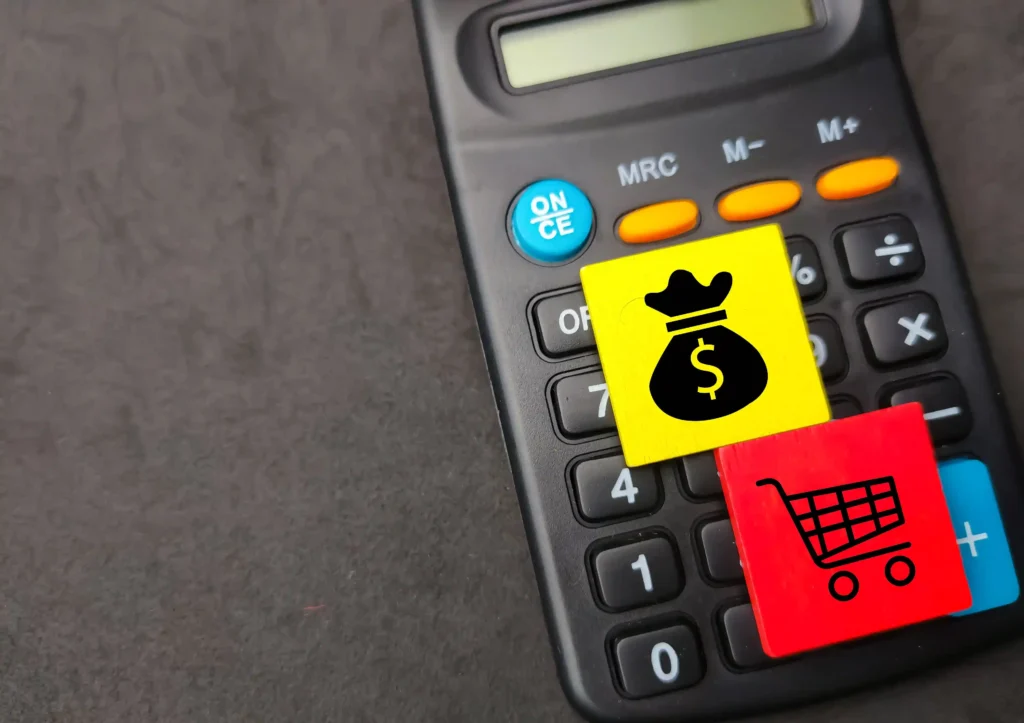 Calculadora com blocos coloridos sobre as teclas, um com símbolo de dinheiro e outro com desenho de carrinho de compras
