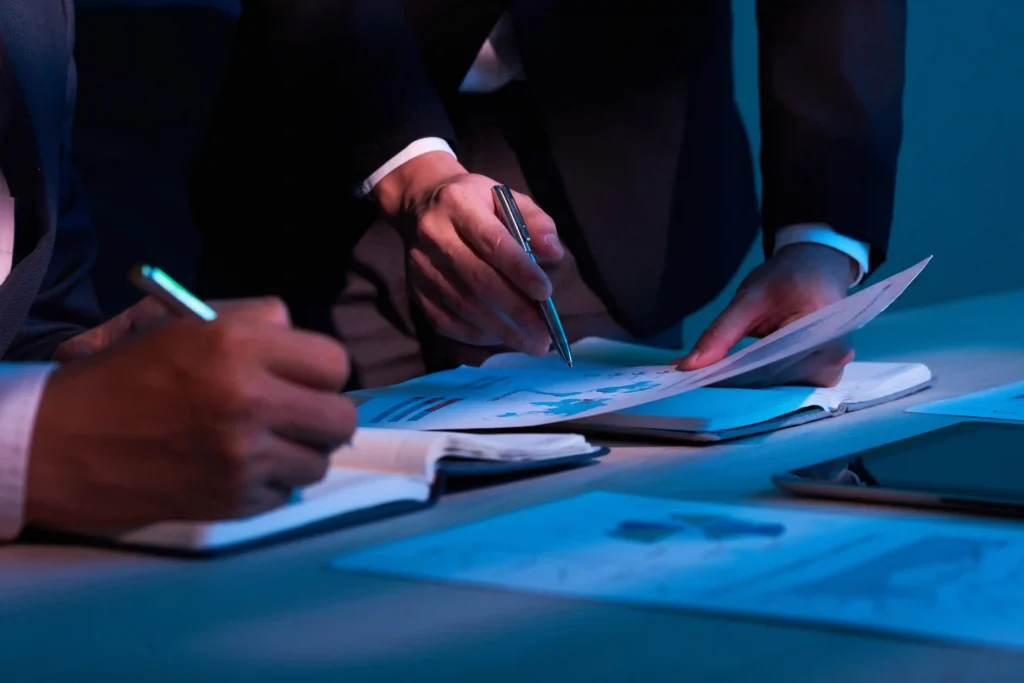 Profissionais analisando documentos com gráficos e fazendo anotações durante uma reunião