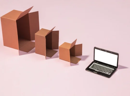 Caixas de papelão abertas em tamanhos diferentes ao lado de um notebook