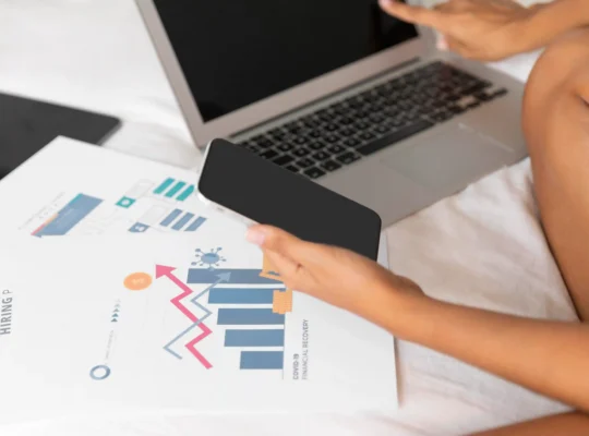 Pessoa analisando gráficos em notebook e smartphone para acompanhar a performance em datas sazonais com a JoomPulse