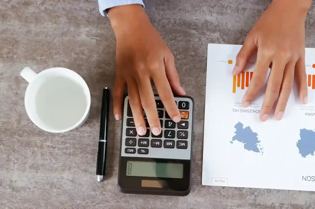 Pessoa usando calculadora para analisar custos de produtos importados e imposto de importação