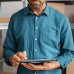 Homem usando tablet em estoque com caixas de produtos ao fundo