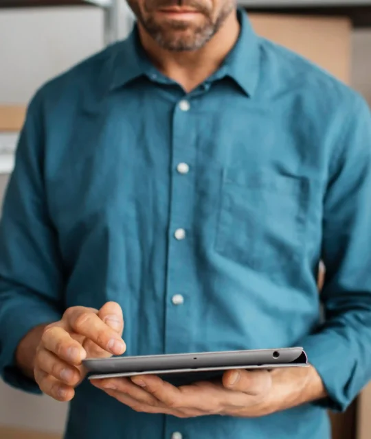 Homem usando tablet em estoque com caixas de produtos ao fundo