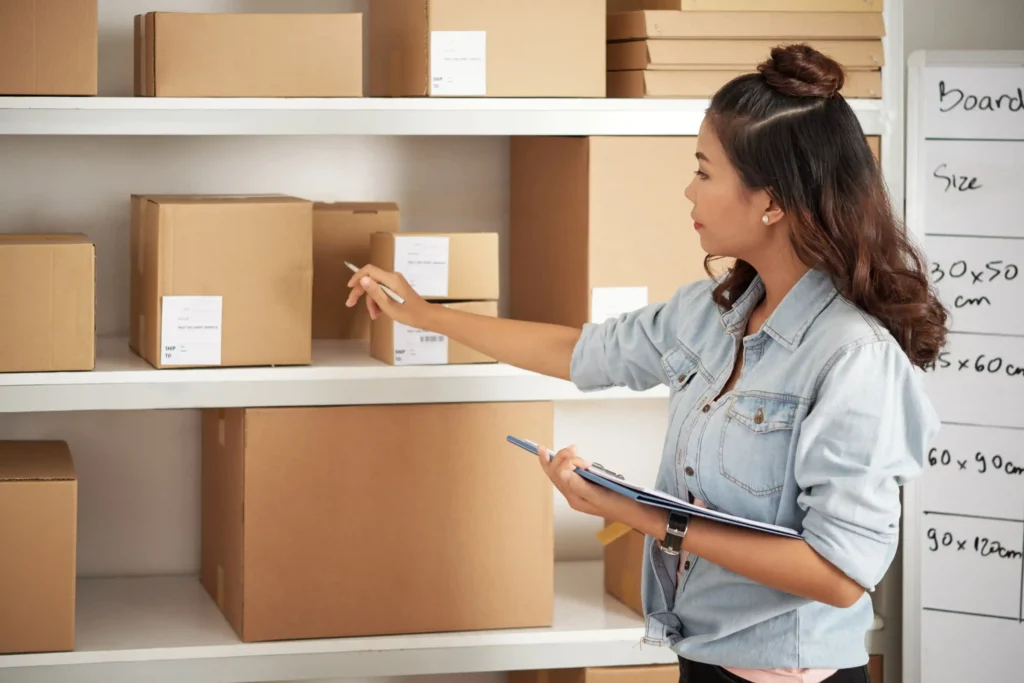 Mulher conferindo caixas e organizando o estoque ecommerce para planejar a reposição de produtos antes da Black Friday