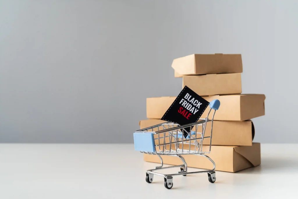 Carrinho de compras com placa de Black Friday diante de caixas de produtos representando a preparação do estoque Black Friday 2026