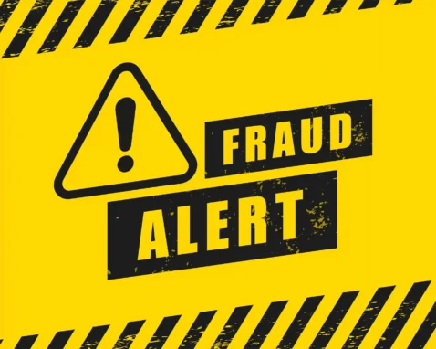 Placa amarela de alerta de fraude com símbolo de atenção e a mensagem “Fraud Alert”