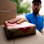 Entregador colocando uma encomenda em uma caixa durante operação de transporte, representando a greve dos Correios e os possíveis atrasos na entrega de pedidos