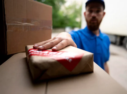 Entregador colocando uma encomenda em uma caixa durante operação de transporte, representando a greve dos Correios e os possíveis atrasos na entrega de pedidos