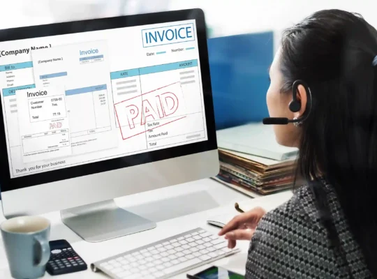Mulher usando headset diante de computador com notas fiscais e comprovantes de pagamento na tela, representando a emissão de nota fiscal ecommerce para vendas online