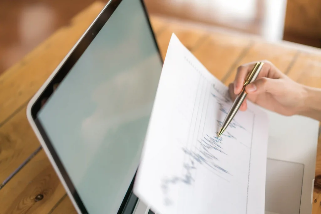 Pessoa analisando uma folha com dados e gráficos ao lado de um notebook, representando o uso do histórico de preços Black Friday para planejar promoções e definir descontos