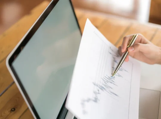 Pessoa analisando uma folha com dados e gráficos ao lado de um notebook, representando o uso do histórico de preços Black Friday para planejar promoções e definir descontos