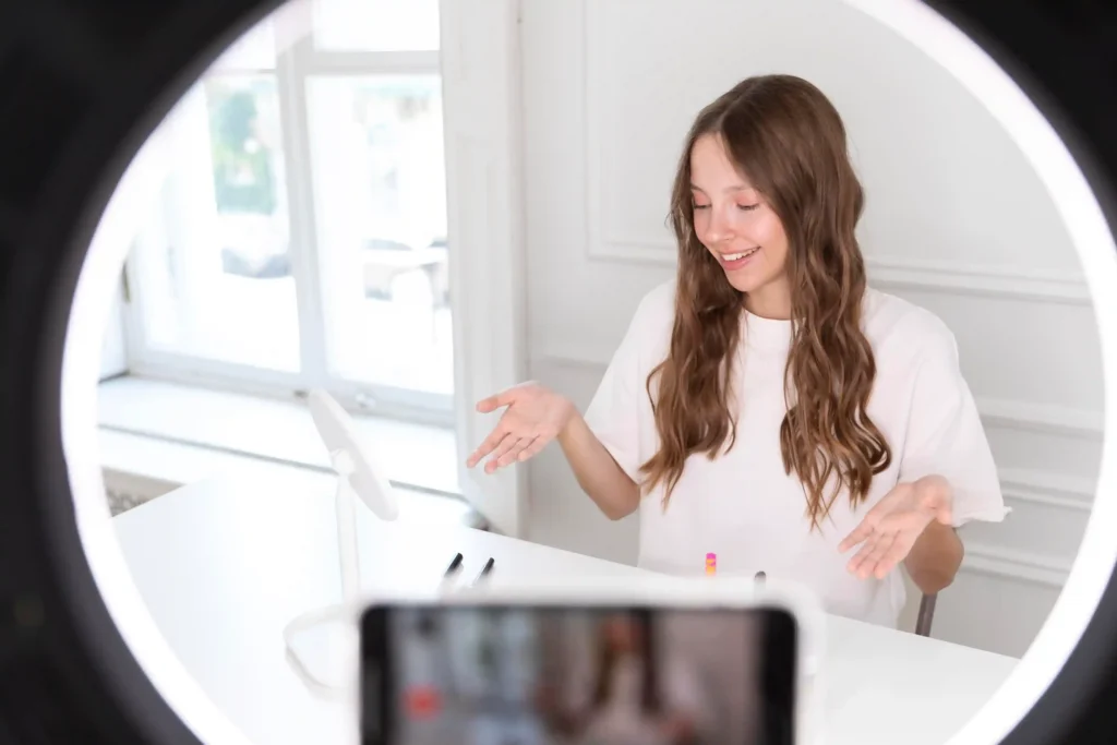 Mulher apresenta um produto diante do celular e de um ring light durante uma transmissão de live commerce