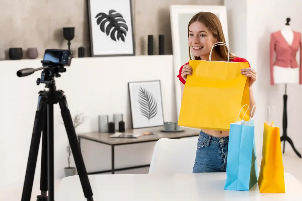 Mulher apresenta uma sacola de compras para uma câmera durante gravação de conteúdo de produtos