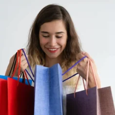 Mulher sorridente segurando sacolas de compras coloridas sobre fundo branco