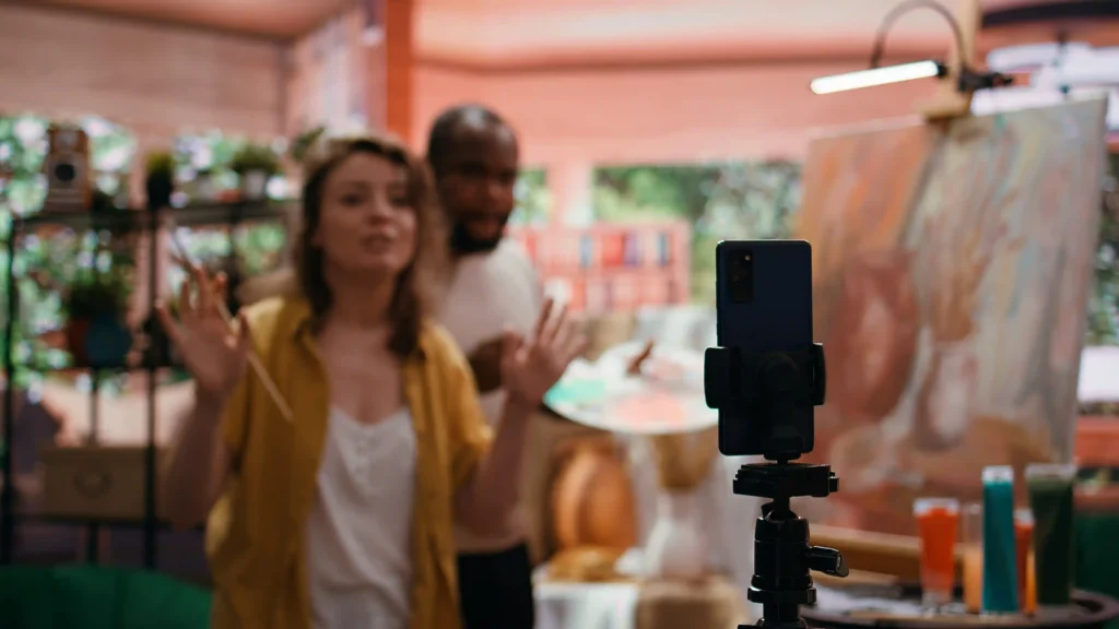 Duas pessoas apresentam produtos diante de um celular durante uma transmissão de vendas ao vivo