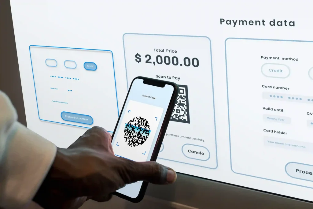 Pessoa utilizando um smartphone para escanear um QR Code de pagamento exibido em uma tela com opções de cartão de crédito